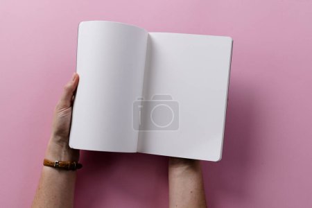 Photo for Hands of caucasian woman holding book with copy space on pink background. Literature, reading, leisure time and books. - Royalty Free Image