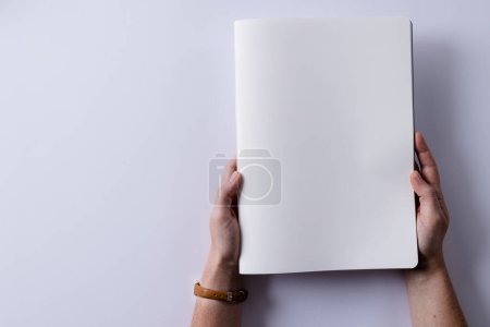 Photo for Hands of caucasian woman holding book with copy space on white background. Literature, reading, leisure time and books. - Royalty Free Image