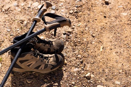 Téléchargez les photos : Bâtons et chaussures de randonnée au sol par temps ensoleillé. Nature, agriculture, été, randonnée et paysage rural. - en image libre de droit