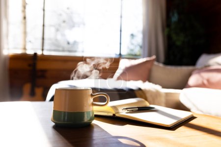 Foto de Taza de café fresco y libro en la mesa en cabaña de madera en el día soleado. Verano, tranquilidad, bebida y relajación. - Imagen libre de derechos