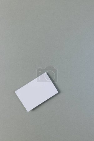Photo for Vertical image of white business card with copy space on grey background. Business, business card, stationery and writing space concept. - Royalty Free Image