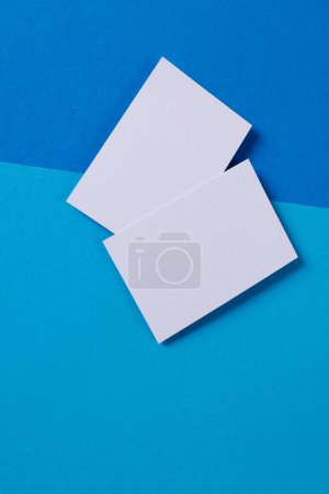 Foto de Imagen vertical de tarjetas de visita blancas con espacio de copia sobre fondo azul claro y oscuro. Concepto de negocio, tarjeta de visita, papelería y espacio de escritura. - Imagen libre de derechos