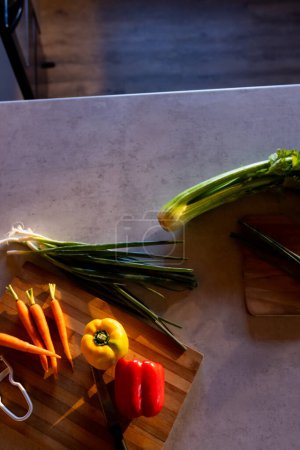 Foto de Imagen vertical de verduras orgánicas sobre tabla de cortar en cocina soleada en cabaña de madera. Alimentación, nutrición, dieta equilibrada y vida saludable. - Imagen libre de derechos
