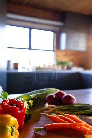 Foto de Imagen vertical de verduras orgánicas sobre tabla de cortar y cuchillo en cocina soleada en cabaña de madera. Alimentación, nutrición, dieta equilibrada y vida saludable. - Imagen libre de derechos