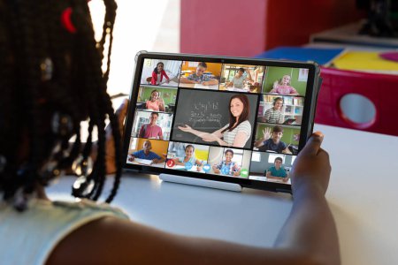 Photo for African american girl looking at teacher and students on digital tablet screen during online class. Unaltered, childhood, technology, education, student, e-learning, video call and home concept. - Royalty Free Image