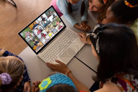 Photo for High angle view of diverse teacher and students studying over video conference on laptop in school. Unaltered, childhood, together, technology, education, student, e-learning, online, classroom. - Royalty Free Image