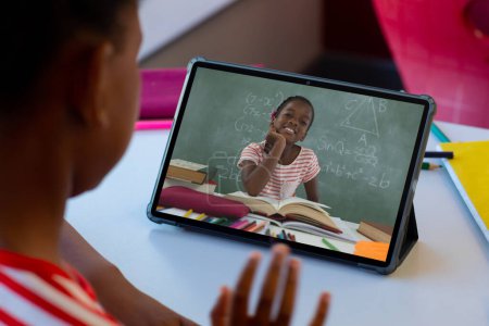 Photo for African american boy discussing mathematics homework with girl over video call on digital tablet. Unaltered, childhood, technology, education, screen, video call, online, student, e-learning and home. - Royalty Free Image
