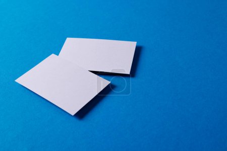 Foto de White business cards with copy space on blue background. Business, business card, stationery and writing space digitally generated image. - Imagen libre de derechos