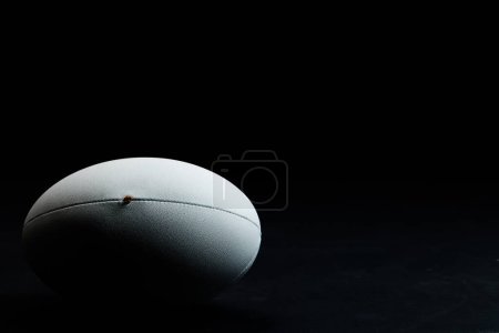Téléchargez les photos : Balle de rugby blanche avec espace de copie sur fond noir. Rugby, sport, international, compétition et jeux image générée numériquement. - en image libre de droit