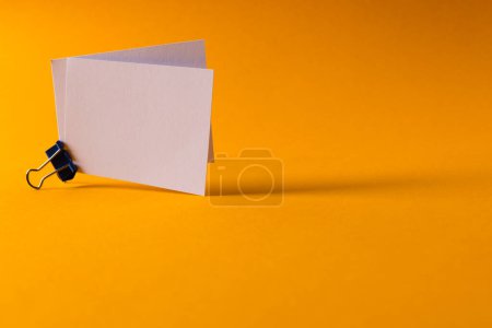 Foto de Tarjetas de visita blancas con clip y espacio de copia sobre fondo naranja. Negocios, tarjetas de visita, papelería y espacio de escritura de imagen generada digitalmente. - Imagen libre de derechos