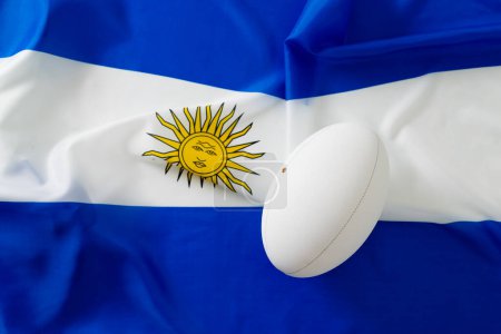 Téléchargez les photos : Ballon de rugby blanc sur le drapeau de l'argentine. Rugby, sport, international, compétition et jeux image générée numériquement. - en image libre de droit