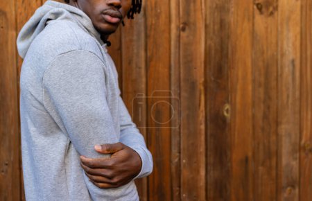 Téléchargez les photos : Midsection de l'homme afro-américain portant un sweat à capuche gris contre une clôture en bois, espace de copie. Mode, vêtements décontractés et vêtements de loisir, inchangés. - en image libre de droit