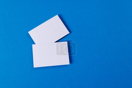 Foto de White business cards with copy space on blue background. Business, business card, stationery and writing space digitally generated image. - Imagen libre de derechos