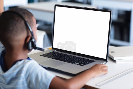 Foto de Vista trasera del chico afroamericano que tiene una videollamada en el portátil con espacio para copiar en casa. Concepto de educación a distancia en línea - Imagen libre de derechos