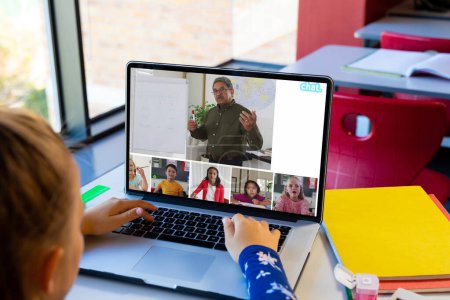 Téléchargez les photos : Fille caucasienne ayant une vidéoconférence avec enseignant masculin et divers étudiants sur ordinateur portable. Concept d'enseignement en ligne à distance - en image libre de droit