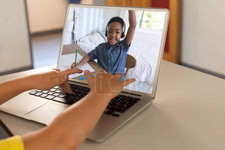 Photo for Mid section of a boy using laptop while having a video call with african american boy at home. Distant learning online education concept - Royalty Free Image