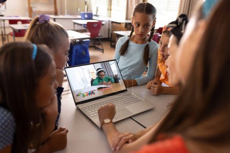 Téléchargez les photos : Asiatique enseignante et divers étudiants ayant un appel vidéo sur ordinateur portable avec un garçon à l'école. Concept d'enseignement en ligne à distance - en image libre de droit