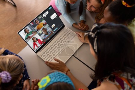 Téléchargez les photos : Asiatique enseignante et divers étudiants ayant une vidéoconférence sur ordinateur portable à l'école. Concept d'enseignement en ligne à distance - en image libre de droit