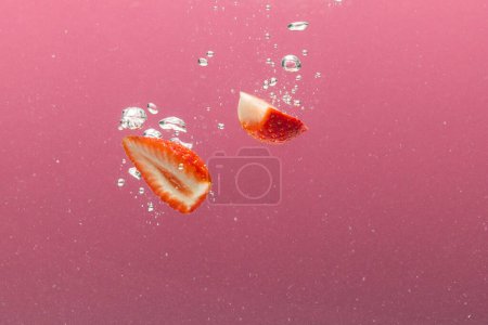 Photo for Close up of strawberries falling into water with copy space on pink background. Fruit, vegan food and colour concept. - Royalty Free Image