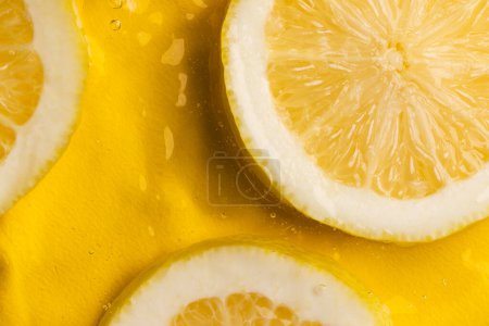 Photo for Close up of lemon slices in water with copy space on yellow background. Fruit, vegan food and colour concept. - Royalty Free Image