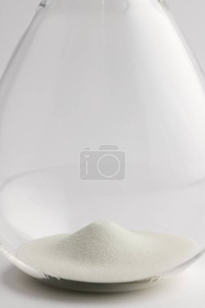 Photo for Close up of hourglass with white sand and copy space on white background. Time, timekeeping, shape and colour concept. - Royalty Free Image