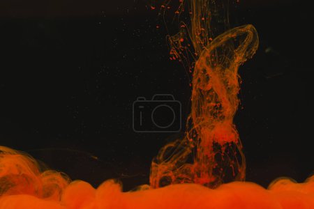Foto de Primer plano de tinta naranja brillante en agua con espacio de copia sobre fondo negro. Concepto de tinta, líquido, forma y color. - Imagen libre de derechos