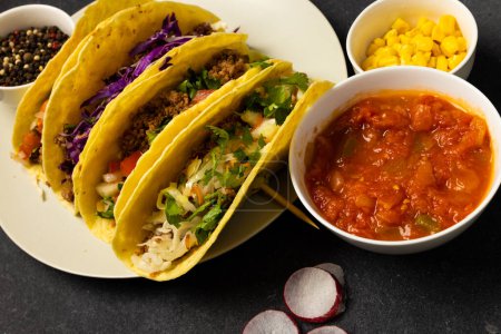 Photo for High angle view of tacos served in plate with black pepper, gravy and corns in bowls on table. meat, vegetable, spice, radish, unaltered, garnish, tortilla, food, fresh and mexican food concept. - Royalty Free Image