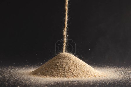 Photo for Close up of sand pouring into heap and copy space on black background. Sand, texture, movement, shape and colour concept. - Royalty Free Image