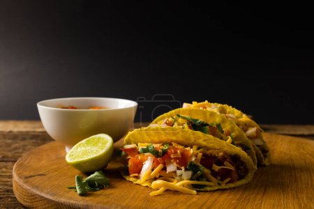 Photo for Close-up of tacos with lemon slice, cilantro and bowl on serving board against black background. copy space, ingredient, tortilla, food, vegetables, cheese and mexican food concept. - Royalty Free Image
