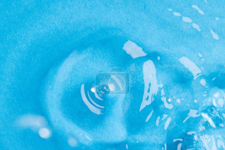 Foto de Primer plano de la gota de agua que cae en el agua con ondas y copiar el espacio en el fondo azul. Concepto de agua, líquido y color. - Imagen libre de derechos