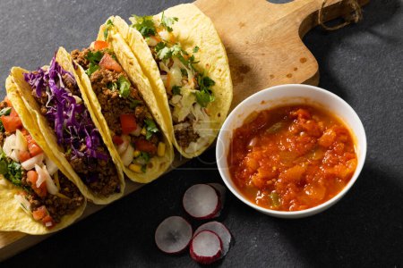 Photo for High angle view of tacos served on wooden board with gravy in bowl and radish slices on table. meat, vegetable, unaltered, tortilla, food, fresh and mexican food concept. - Royalty Free Image