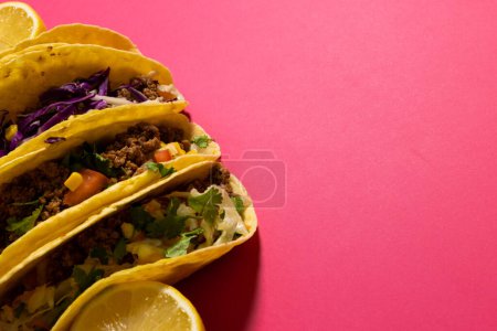 Hochwinkelansicht von Tacos mit Zitronenscheiben über rosa Hintergrund, Kopierraum. Gemüse, Fleisch, Tortilla, Lebensmittel, frisches und mexikanisches Essenskonzept.