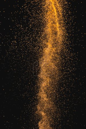 Photo for Close up of orange sand thrown in the air and copy space on black background. Sand, texture, movement, shape and colour concept. - Royalty Free Image