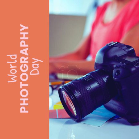 Téléchargez les photos : Journée mondiale de la photographie texte sur l'orange sur la caméra sur le bureau de la femme biraciale à l'aide d'un ordinateur. Célébration mondiale de la campagne photographique, image générée numériquement. - en image libre de droit