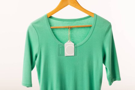 Photo for Green t shirt with tag on hanger with copy space on white background. Fashion, clothes, colour and fabric concept. - Royalty Free Image