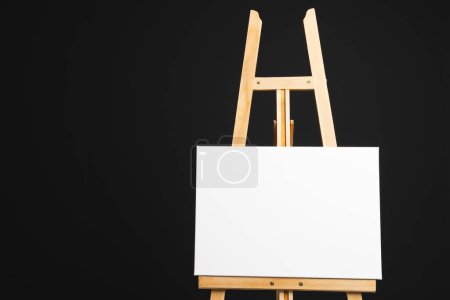 Photo for White canvas on wooden easel and copy space on black background. Signage, writing space and advertising concept. - Royalty Free Image