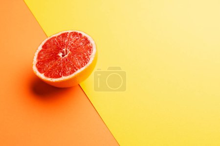 Photo for Close up of half of red grapefruit and copy space on orange and yellow background. Fruit, food, freshness and colour concept. - Royalty Free Image