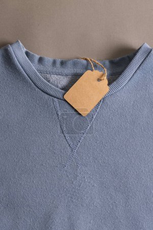 Foto de Primer plano de la camiseta azul con etiqueta y espacio de copia sobre fondo marrón. Moda, ropa, color y concepto de tela. - Imagen libre de derechos