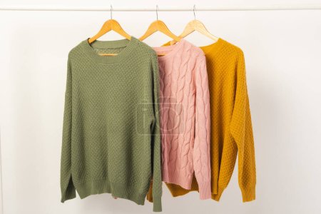 Photo for Three sweaters hanging from clothes rail with copy space on white background. Fashion, clothes, colour and fabric concept. - Royalty Free Image