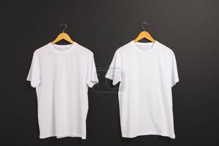 Photo for Two white t shirts on hangers and copy space on black background. Fashion, clothes, colour and fabric concept. - Royalty Free Image