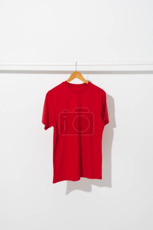 Photo for Red t shirt on hanger hanging from clothes rail with copy space on white background. Fashion, clothes, colour and fabric concept. - Royalty Free Image
