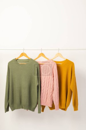 Photo for Three sweaters hanging from clothes rail with copy space on white background. Fashion, clothes, colour and fabric concept. - Royalty Free Image