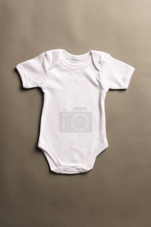Téléchargez les photos : Pose plate de bébé blanc grandir avec l'espace de copie sur fond gris. Mode bébé, vêtements, concept de couleur et de tissu. - en image libre de droit