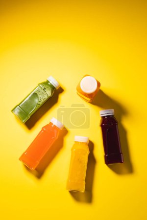 Foto de Cierre de botellas de plástico con jugo fresco y espacio para copiar sobre fondo amarillo. Concepto de frutas, bebidas, alimentos, frescura y color. - Imagen libre de derechos