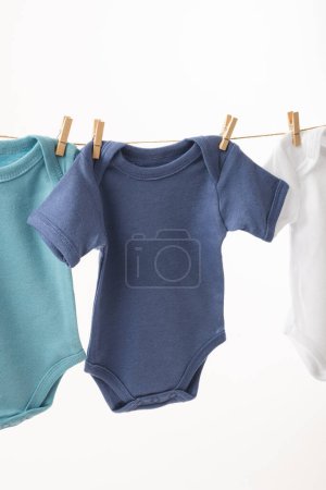 Photo for Three baby grows hanging from clothes line with pegs and copy space on white background. Baby fashion, clothes, colour and fabric concept. - Royalty Free Image