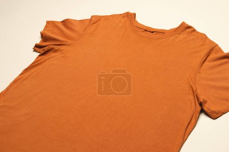 Foto de Primer plano de la disposición plana de camiseta naranja y espacio de copia sobre fondo amarillo. Moda, ropa, color y concepto de tela. - Imagen libre de derechos