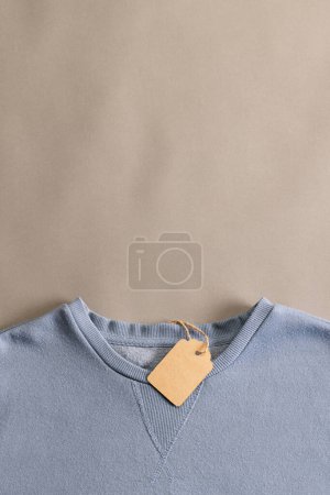 Foto de Primer plano de la camiseta azul con etiqueta y espacio de copia sobre fondo marrón. Moda, ropa, color y concepto de tela. - Imagen libre de derechos