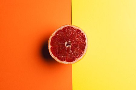 Photo for Close up of half of red grapefruit and copy space on orange and yellow background. Fruit, food, freshness and colour concept. - Royalty Free Image