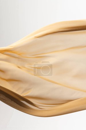 Foto de Primer plano de tela de seda brillante dorado con espacio para copiar sobre fondo blanco. Textura, tela, tela, color y material. - Imagen libre de derechos