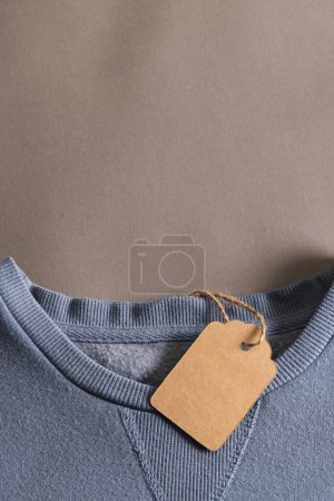 Téléchargez les photos : Gros plan de t-shirt bleu avec étiquette et espace de copie sur fond brun. Mode, vêtements, concept de couleur et de tissu. - en image libre de droit